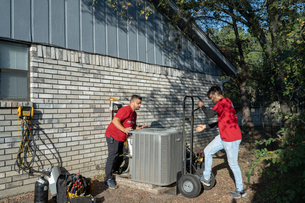 Two men are working on a new air conditioner.