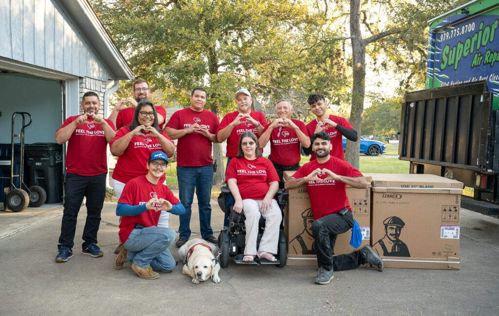 A group of people in red shirts standing next to boxes.